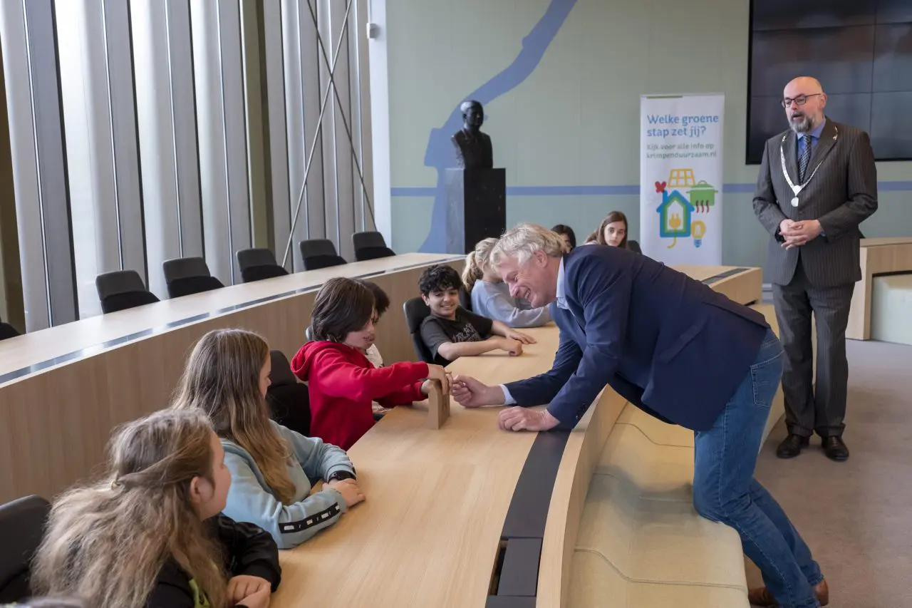 Wethouder Wubbo Tempel geeft het klimaatspel aan een leerling van de Rudolf Steinerschool in Krimpen.