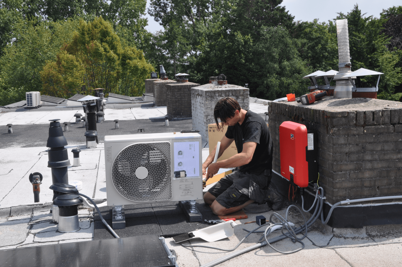 Installateur plaats hybride warmtepomp op het dak.