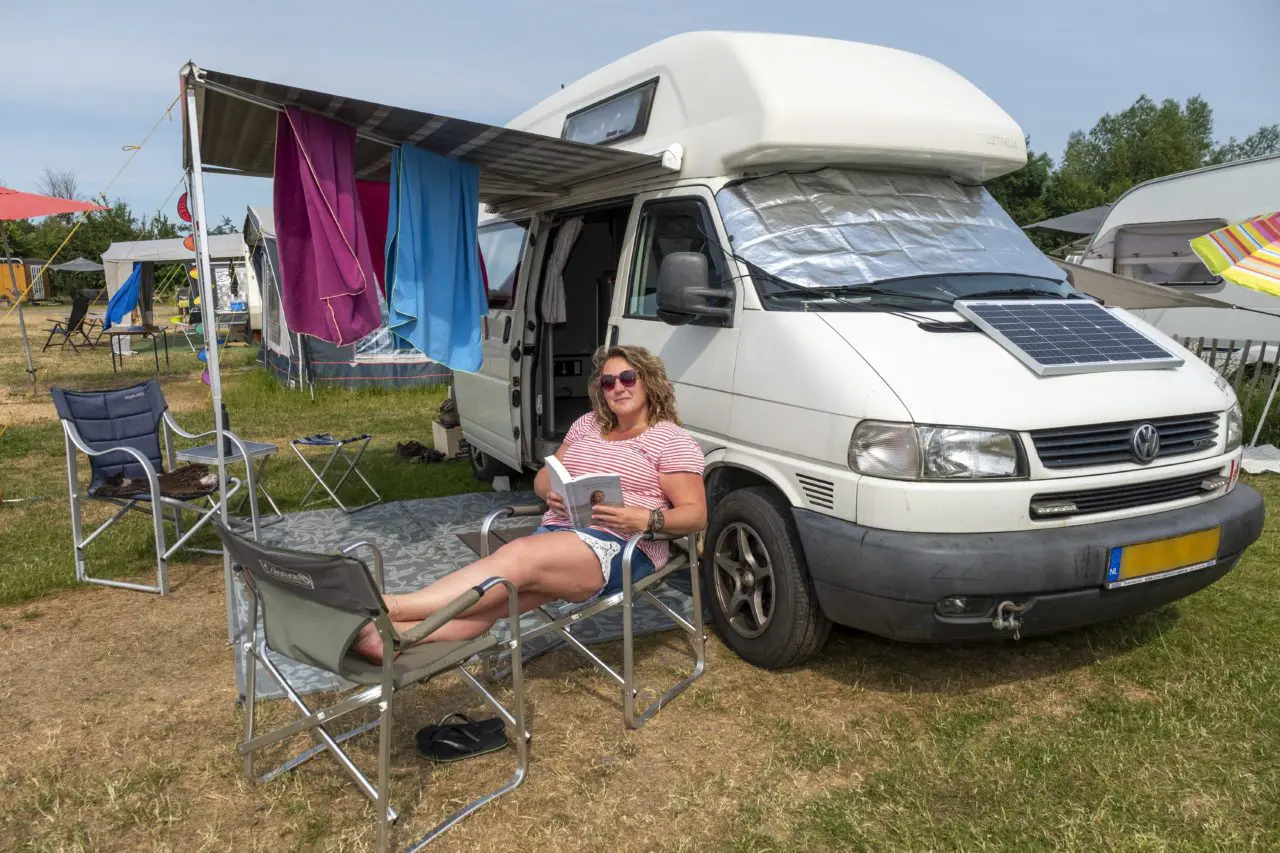 Patricia Oskam uit Krimpen aan den IJssel leest een boek bij haar kampeerbus, waarmee ze duurzaam op vakantie gaat.